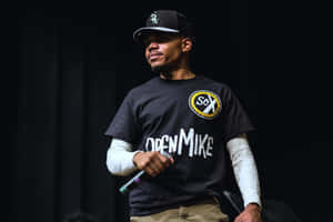 A Man In A Black Shirt Standing On Stage Wallpaper