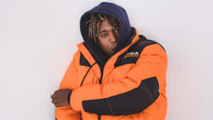 A Man In An Orange Jacket Leaning Against A Wall Wallpaper