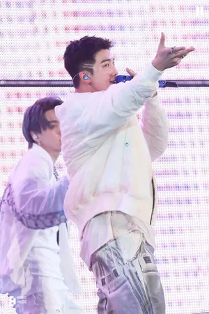 A Man Is Singing Into A Microphone While Another Man Is Standing Wallpaper