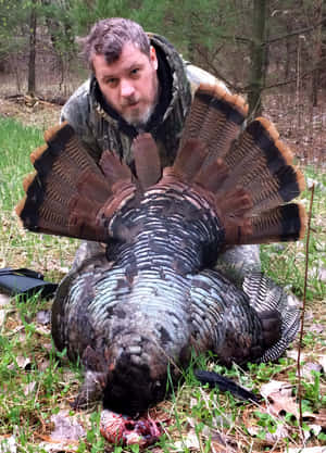 A Man Kneeling Down Next To A Turkey Wallpaper