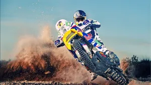 A Man Riding A Dirt Bike On A Dirt Track Wallpaper