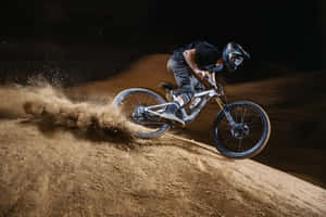 A Man Riding A Mountain Bike On A Dirt Hill Wallpaper