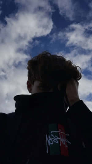 A Man With A Black Hoodie And A Cloudy Sky Wallpaper