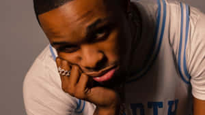 A Man With A Blue And White Shirt Is Posing With His Hand On His Chin Wallpaper