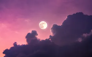 A Moon Is Seen Through A Purple Cloudy Sky Wallpaper