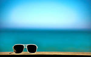 A Pair Of Sunglasses On A Wooden Bench Wallpaper