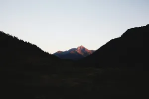 A Peaceful Vista Of A Minimalist Mountain Rises Into A Beautiful Blue Sky Wallpaper