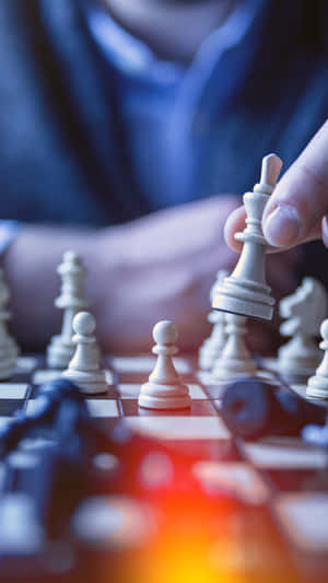 A Person Is Playing Chess On A Board Wallpaper