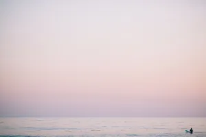 A Person Is Standing On The Beach At Sunset Wallpaper