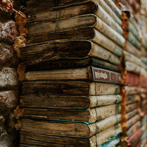 A Pile Of Vintage Books In A Library Wallpaper