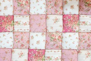 A Pink And White Quilt With Floral Patterns Wallpaper