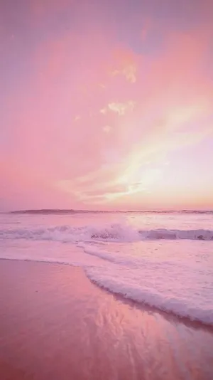 A Pink Sunset On A Beach With Waves Wallpaper