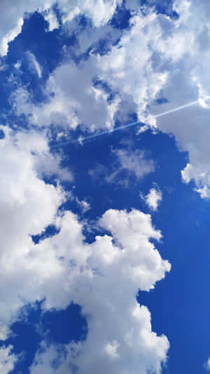 A Plane Flying Through The Sky With Clouds Wallpaper