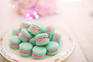A Plate Of Pink And Green Macarons On A Table Wallpaper