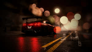 A Red Car Is Driving Down The Street At Night Wallpaper