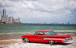 A Red Car Parked On The Beach Wallpaper