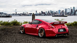 A Red Sports Car Parked In Front Of A City Wallpaper