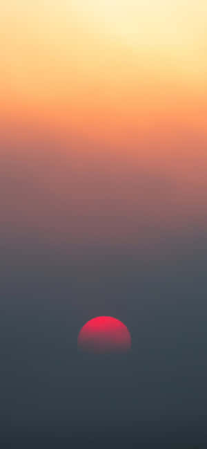 A Red Sun Rising Over A Fog Filled Sky Wallpaper