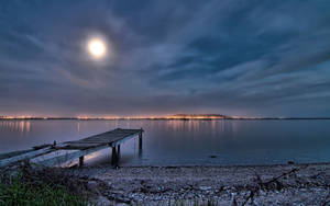A Serene Night At The Beach Illuminated By Twinkling Lights Wallpaper
