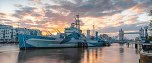 A Ship Docked In The River Near A City Wallpaper