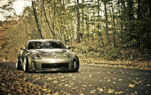 A Silver Car Is Parked On A Road In The Woods Wallpaper