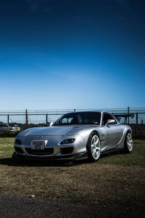 A Silver Car Parked On A Grassy Field Wallpaper