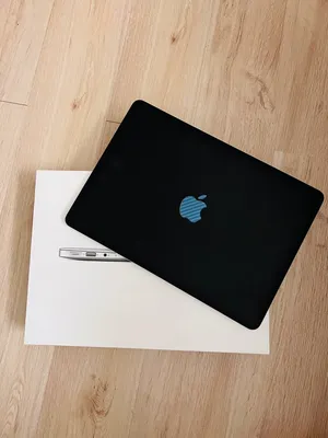 A Sleek Black Macbook Sitting On A White Desk Wallpaper