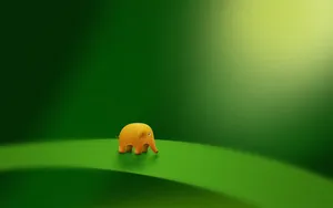 A Small Yellow Elephant Standing On A Green Leaf Wallpaper