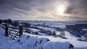 A Snow Covered Field With A Fence And Sun Wallpaper