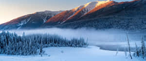 A Snow Covered Mountain Range With Trees And A Lake Wallpaper