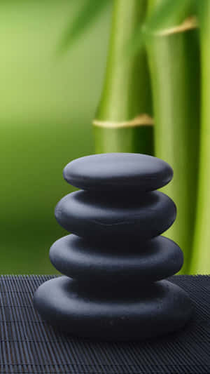 A Stack Of Black Stones On A Bamboo Mat Wallpaper