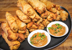 A Stack Of Delectable Egg Rolls With Savory Peanut Sauce Wallpaper