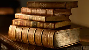 A Stack Of Old Books On A Table Wallpaper