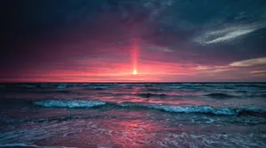 A Sunset Over The Ocean With A Red Light Shining Wallpaper