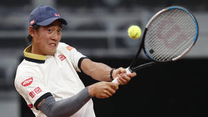 A Tennis Player Swinging His Racket At A Ball Wallpaper