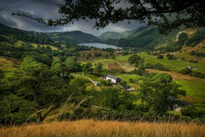 A View Of A Valley With A House And Trees Wallpaper