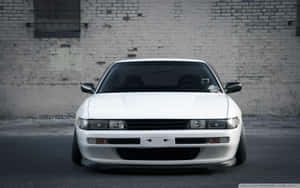 A White Car Parked In Front Of A Brick Wall Wallpaper