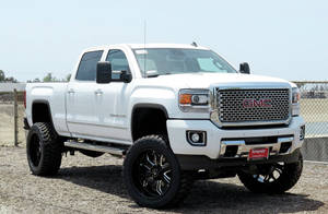 A White Gmc Sierra Truck Is Parked In A Dirt Lot Wallpaper