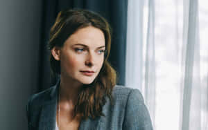 A Woman In A Gray Suit Looking Out The Window Wallpaper