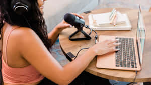 A Woman Is Using A Laptop And A Microphone Wallpaper