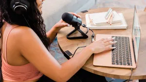 A Woman Is Using A Laptop And A Microphone Wallpaper
