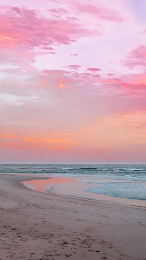 A Woman Is Walking On The Beach At Sunset Wallpaper