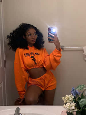 A Woman Taking A Selfie In An Orange Sweatsuit Wallpaper