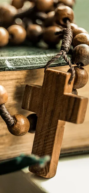 A Wooden Rosary Is Sitting On Top Of A Book Wallpaper