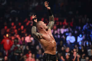 A Wrestler With Tattoos Is Holding His Arms Up In The Air Wallpaper