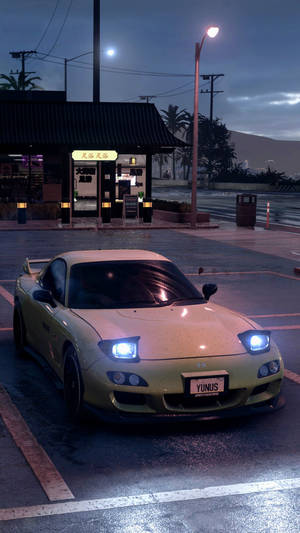 A Yellow Car Is Parked In A Parking Lot At Night Wallpaper