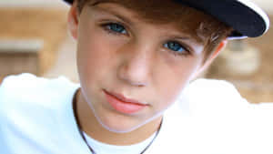 A Young Boy Wearing A Baseball Cap And A Necklace Wallpaper