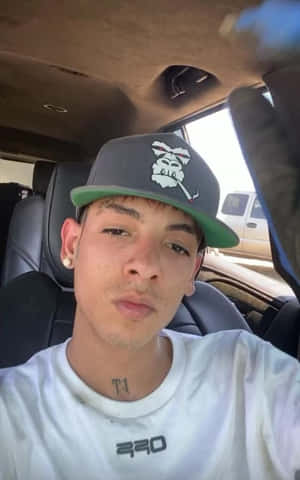 A Young Man In A Hat Is Sitting In A Car Wallpaper