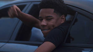 A Young Man Is Sitting In A Car And Waving His Hand Wallpaper