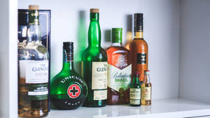 Alcohol Bottles Collection On White Shelf Wallpaper
